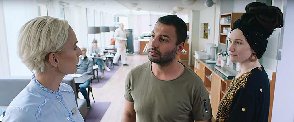 En servitris pratar med två personer i entrén i till en restaurang.
