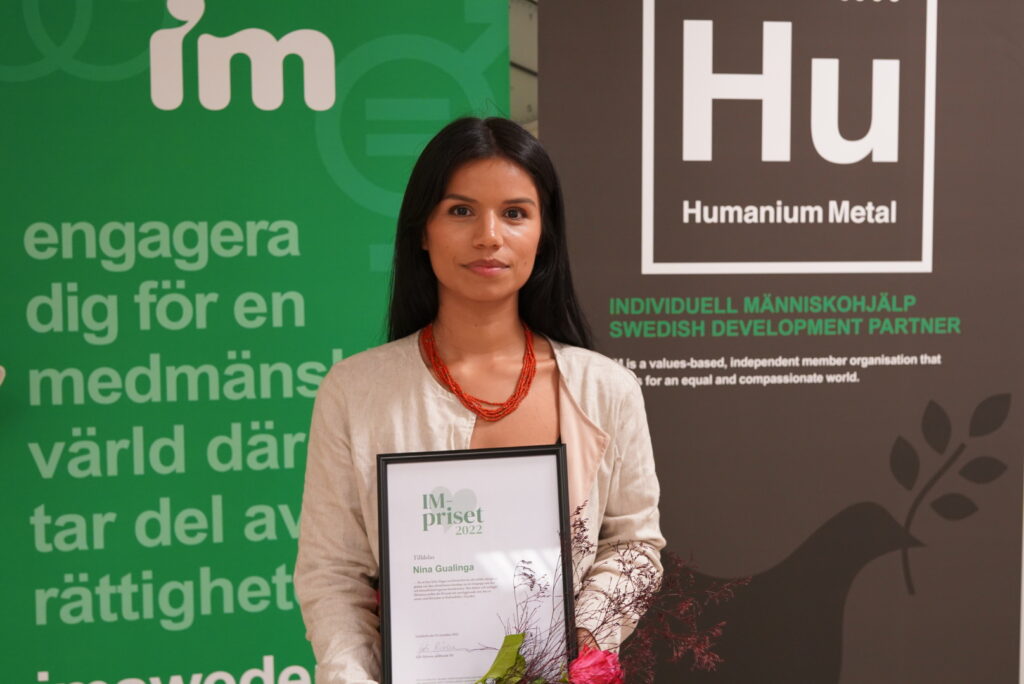 Nina Gualinga med blommor och diplom.