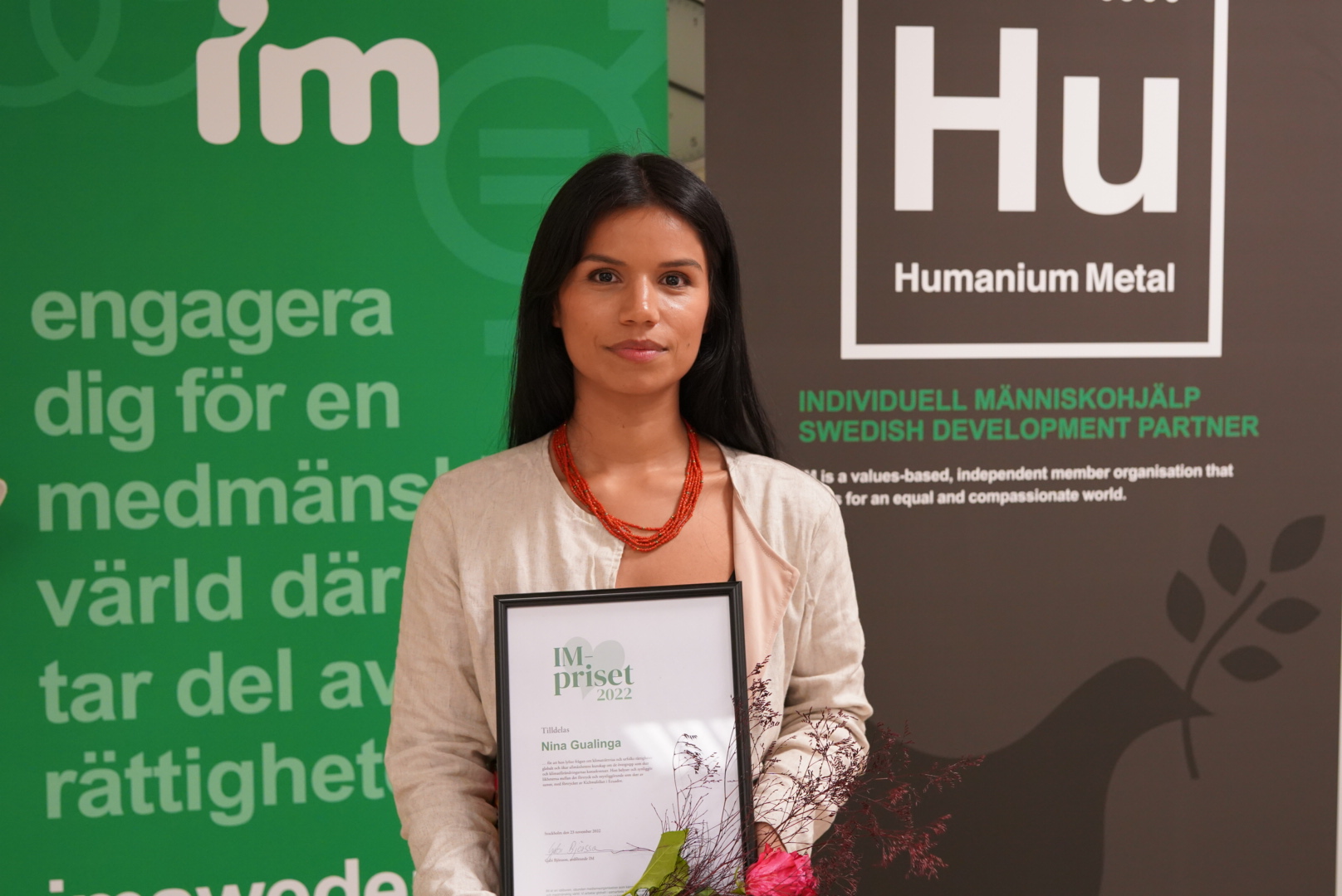 Nina Gualinga med blommor och diplom.